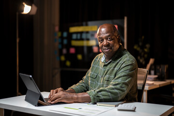 Fototapeta premium A man is sitting at a desk with a laptop and a notebook