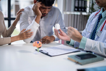 A man is sitting at a desk with a doctor and a woman