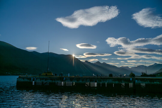 Sunrise over the norway romsdalsfjorden fjords in Andalsnes Harbor with beautiful celeste park benches and the first sun rays shining on the ocean waters of the bay