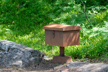 art installation: rusty locked box or coffin in the woods in Romsdalseggen norway