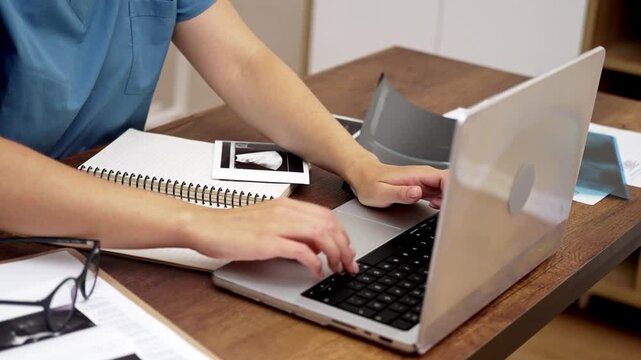 Ultrasound Interpretation: Dressed in blue scrubs, the doctor interprets ultrasound results, making comprehensive notes on her laptop for detailed documentation. 