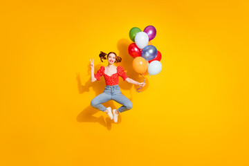 Photo portrait of young red hair funky positive girl wearing blouse and jeans flying air balloons v sign isolated on yellow color background