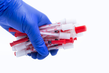Blue gloved hand holding lots of insulin syringe isolated on white background.