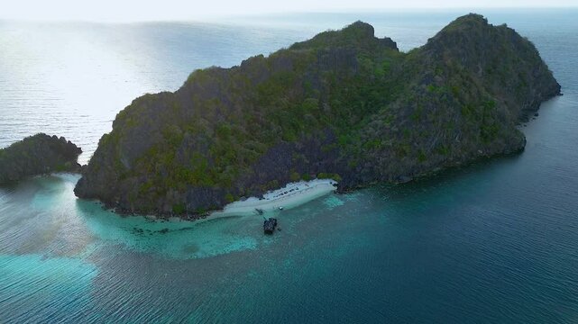 Coron island beach sits below steep limestone hills with turquoise shallows small boats pale sand and open sea under hazy daylight