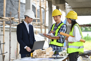 Male project manager and engineers discussing project details at building site