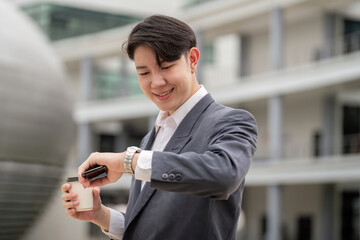 Young Businessman Checking Time on Watch While Holding Coffee Cup in Modern Office Building