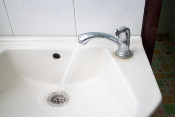 Water flowing from the faucet in the washbasin.