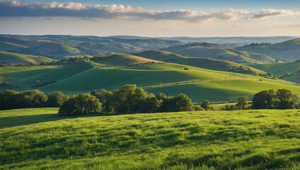 Rolling countryside hills with green meadows under a setting sun and a partially cloudy sky.