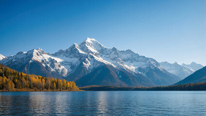 Naklejka premium Snowcapped mountains reflecting in a crystal-clear lake surrounded by forested hills under a bright blue sky.