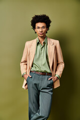 A stylish young curly African American man in a suit and tie standing confidently in front of a vibrant green wall.