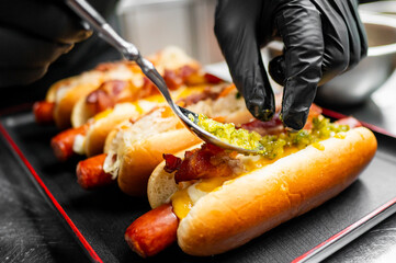 Close-up of colorful hot dogs with various toppings on a black surface