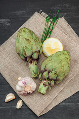 Fresh green artichokes cooking on wooden background. Traditional seasonal ingredients