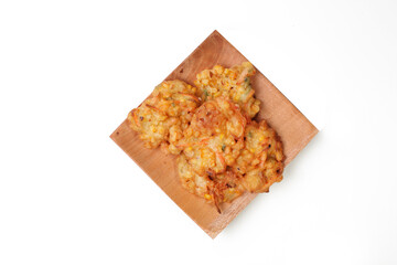 Bakwan Jagung or Dadar Jagung or Dadar Jagung Manado, is Manadonese style of corn fritters. Indonesian snack made from corn and flour. Served on a wooden plate. White background. good for article