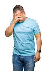 Middle age arab man wearing blue t-shirt over isolated background with sad expression covering face with hands while crying. Depression concept.