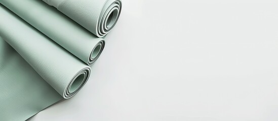 Modern pastel grey green yoga mat rolled on a white background with a minimalist design creating a serene copy space image