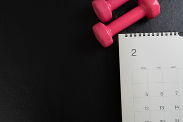 Time for exercising equipment dumbbell and calendar with black background, sport and healthy concept