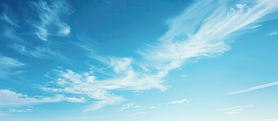A serene scene of clear blue skies with wispy white clouds peacefully drifting in the airy atmosphere creating a tranquil copy space image