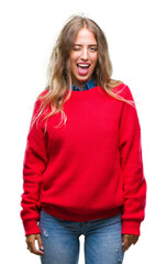 Beautiful young blonde woman wearing winter sweater over isolated background winking looking at the...