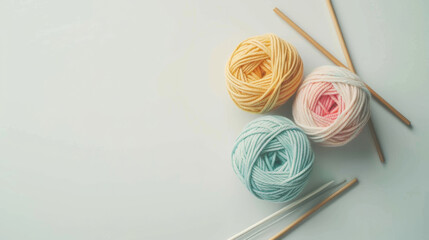 Pastel Yarn Balls and Wooden Knitting Needles on White Background
