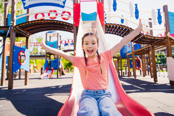 Portrait of adorable funny little girl have fun outside slide playground hill activity enjoy summer weekend pastime fresh air outdoor