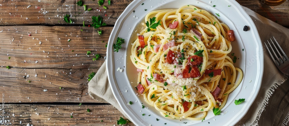 Fototapete Plate of spaghetti carbonara with white sauce ham and bacon on a wooden table with a background suitable for adding text or an image. with copy space image. Place for adding text or design