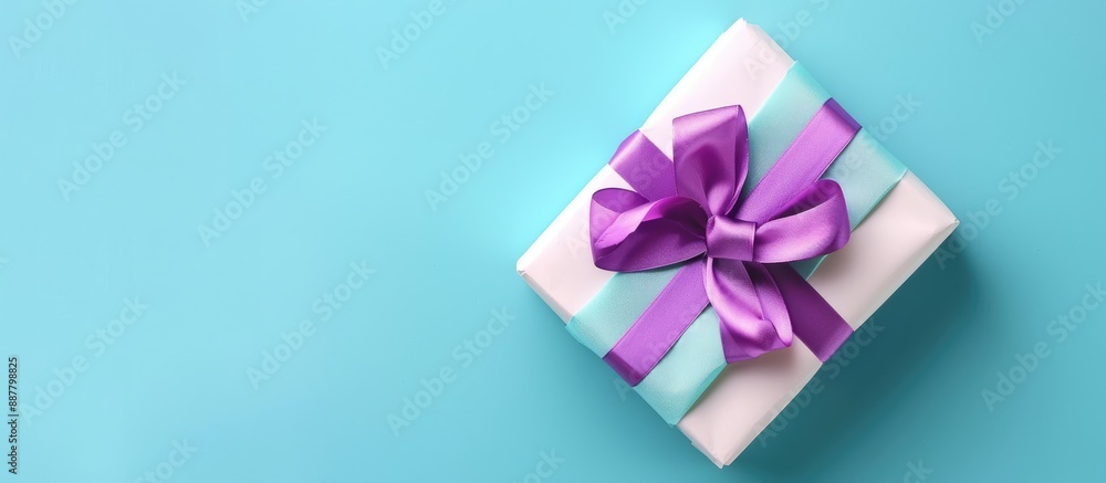 Aufkleber top view of a gift box wrapped in paper with a purple ribbon displayed on a colored table with a blu