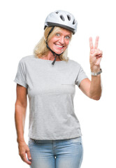 Middle age caucasian cyclist woman wearing safety helmet over isolated background smiling with happy face winking at the camera doing victory sign. Number two.