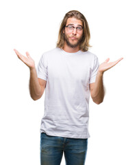 Young handsome man with long hair wearing glasses over isolated background clueless and confused...