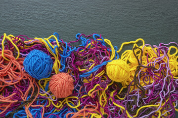 Tangled threads and attempt to wind them into balls. Dark background, flat lay, copy space