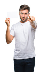 Young handsome man holding blank card over isolated background pointing with finger to the camera and to you, hand sign, positive and confident gesture from the front