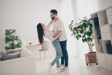 Full body photo of cheerful cute young couple enjoy weekend couple hugging dancing wife husband buy new apartment indoors inside house home