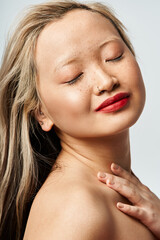 Fototapeta premium Asian woman in vibrant clothing, eyes closed, hands on chest