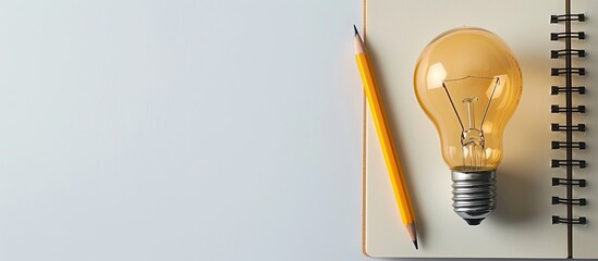 Minimalist concept with a light bulb notebook and pencil on a white background representing business planning with copy space image
