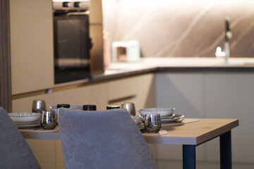 Close-up view of dining table set and modern kitchen in bokeh blurred background