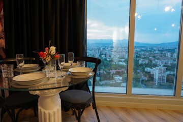 Romantic dining table setting next to window with city view in a luxury apartment hotel room