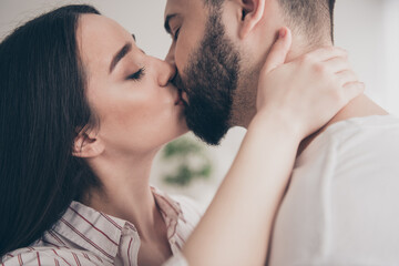 Fototapeta premium Photo of cheerful cute young couple enjoy weekend couple kissing lips wife husband buy new apartment indoors inside house home