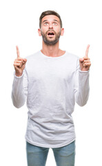 Young handsome man over isolated background amazed and surprised looking up and pointing with fingers and raised arms.