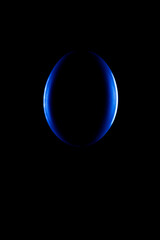 Blue oval outline, bright silhouette on a black background. The silhouette of an egg on a black background. Design element