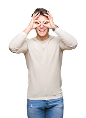 Naklejka premium Young handsome man over isolated background doing ok gesture like binoculars sticking tongue out, eyes looking through fingers. Crazy expression.