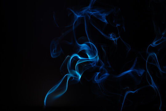 Blue smoke isolated on a black background. A thin curved line of smoke, steam from a burnt candle to overlay on your photos