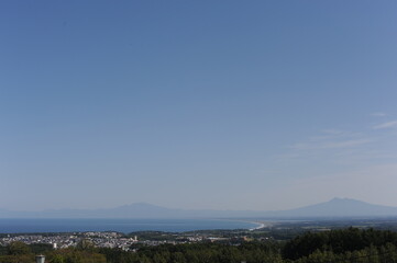 Panorama of Abashiri city with Mount Rausu and Mount Iō in the background on a sunny day with blue sky in summer, Hokkaido island, Japan
