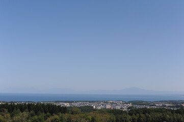 Panorama of Abashiri city with Mount Rausu and Mount Iō in the background on a sunny day with blue sky in summer, Hokkaido island, Japan