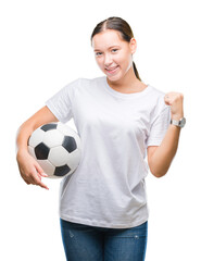 Young beautiful caucasian woman holding soccer football ball over isolated background screaming proud and celebrating victory and success very excited, cheering emotion