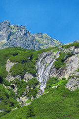 A waterfall flows down a mountain slope. Beautiful summer landscape in the Tatra Mountains, Poland.