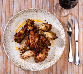 Plate with fried chicken wings on wooden table background