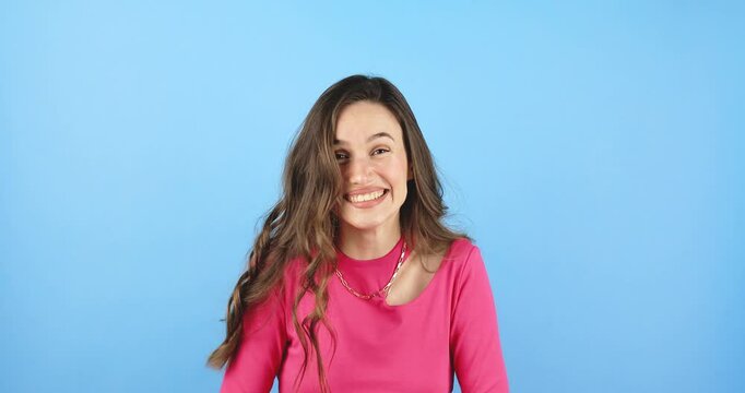 Amazed excited woman hairstyle in pink long sleeves top open mouth in surprise looking at camera with big eyes, shocked isolated on blue background. Oh my god wow, yes gesture, win symbol.