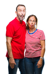Fototapeta premium Middle age hispanic couple in love over isolated background making fish face with lips, crazy and comical gesture. Funny expression.