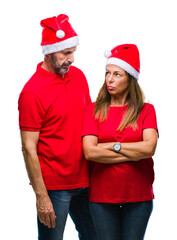 Middle age hispanic couple wearing christmas hat over isolated background skeptic and nervous, disapproving expression on face with crossed arms. Negative person.