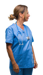 Middle age senior nurse doctor woman over isolated background looking to side, relax profile pose...