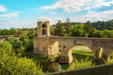 Obraz premium Besalu, Girona, Catalonia, Spain. Famous landmark. Old medieval Romanesque bridge Besalu over the river Fluvia on a sunny summer day.